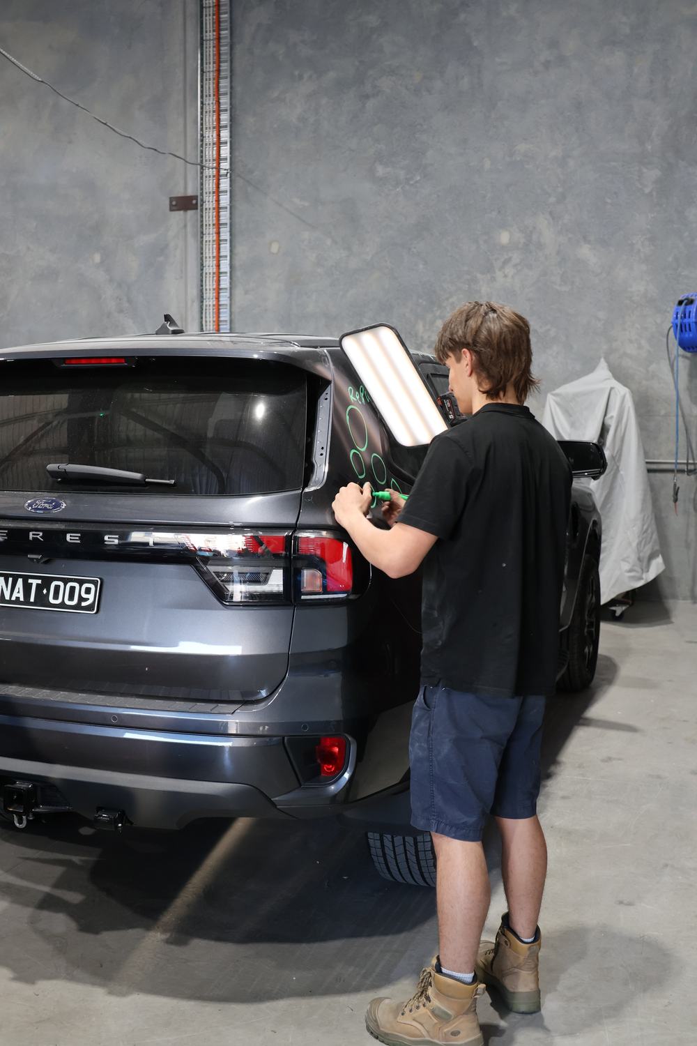 MRP technician marking dents for repair with a PDR light board — Redland Bay workshop